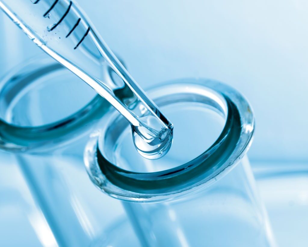 Liquid being dripped into a test tube opening