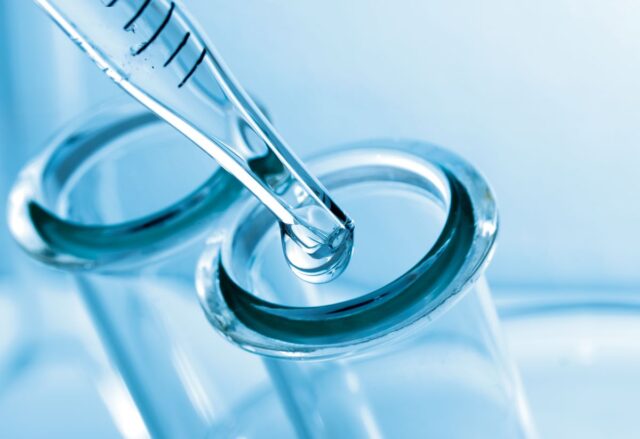 Liquid being dripped into a test tube opening