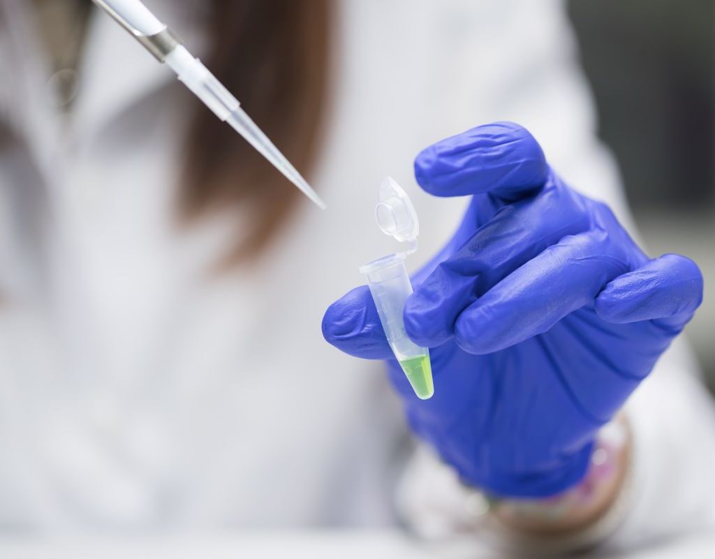 Lab technician adding liquid into a container
